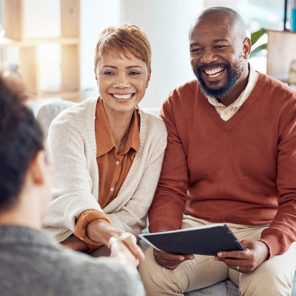 A financial advisor shakes hands with an older couple to discuss investments, insurance and retirement.